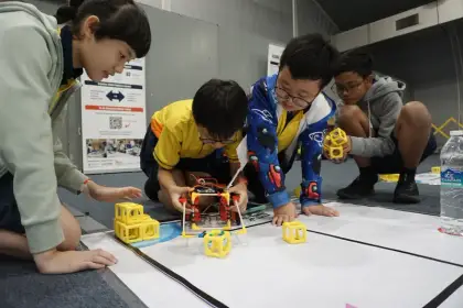 Kneeling over their build at the Global Robotics Games
