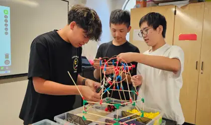 Three boys build a colourful stick structure