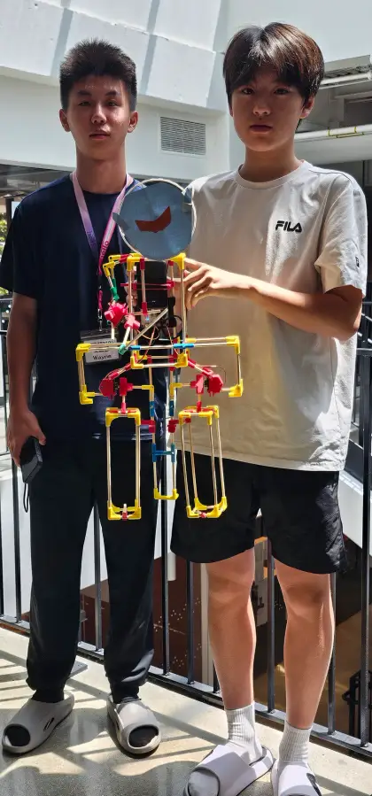 Two teens beside their tall humanoid robot