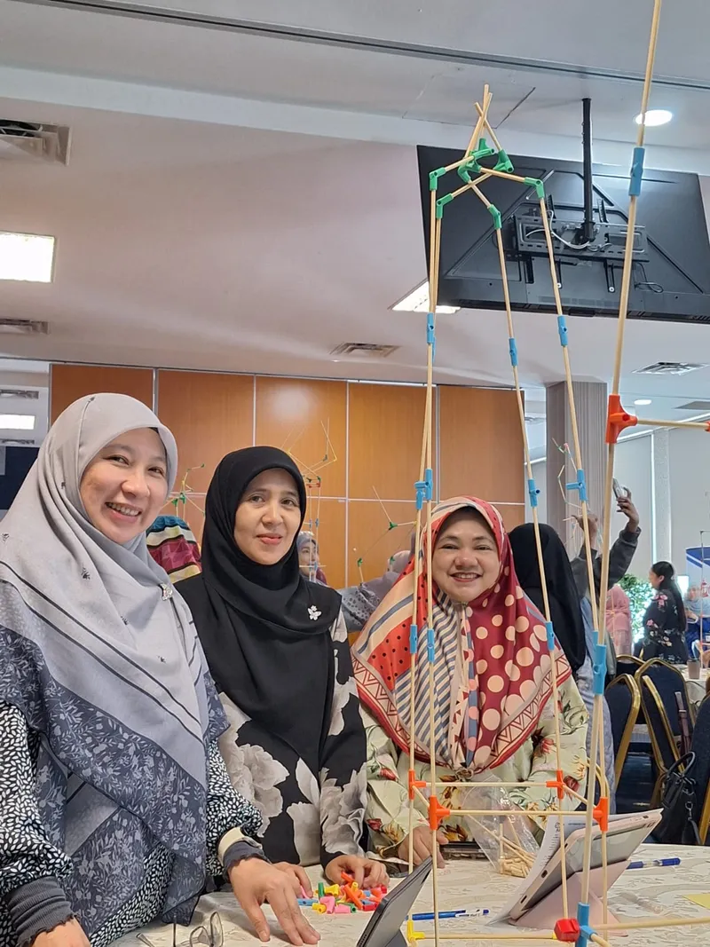 Teachers standing beside the tall structure they built