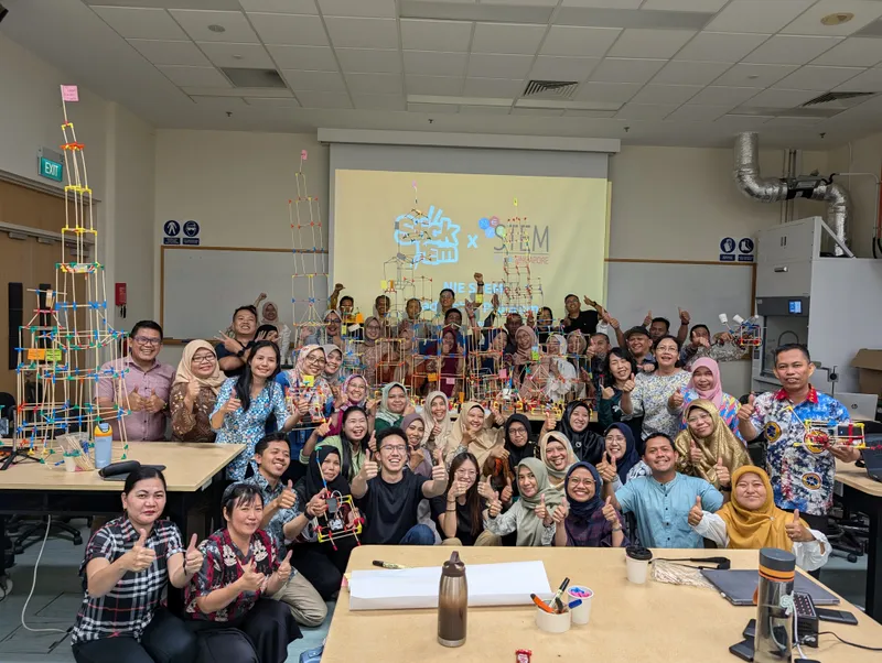 Indonesian teachers cheering beside their tall tower at NIE